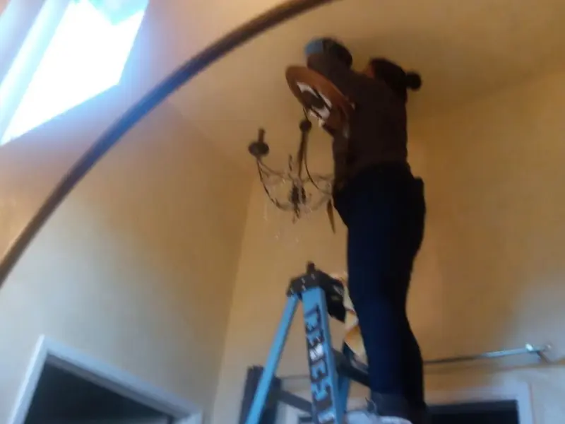Electrician installing a chandelier in a Minneapolis residence